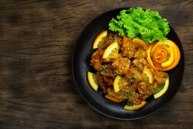 Portakallı, bol yağda kızartılmış, portakallı, tatlı ve ekşi, siyah tabakta Amerika 'nın en popüler Çin yemeği sebze stili üst görünüm dekorasyonu.