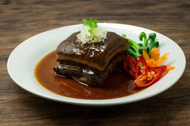 Kahverengi soslu soğanlı pirzola dilimlenmiş Tayvan yemeği füzyon stili oyulmuş taze soğanlı biber ve ahşap arka planda havuç çiçeği şeklinde havuç.