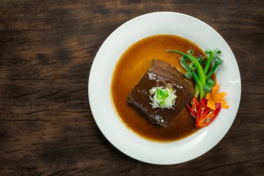 Kahverengi soslu soğanlı pirzola dilimlenmiş Tayvan yemeği füzyon stili oyulmuş taze soğanlı biber ve ahşap arka planda havuç çiçeği şeklinde havuç.