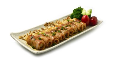 Yakitori ızgara domuz pastırması ve soslu altın iğneli mantar soslu teriyaki serpiştirilmiş soğan Japon yemeği füzyon stili mükemmel barbekü sosu iyi pişmiş salatalıklı maydanoz ve domatesli meze.