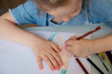 Çocuk kalemleri beyaz kağıda renkli kalemlerle çizerler.
