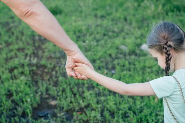 Babalar kızlarının elini tutar ve hafif giysiler içinde sokakta yürürler.