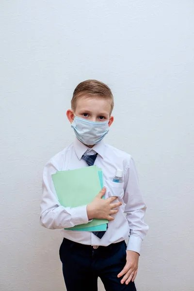 Um menino mascarado com uma camisa branca e gravata está segurando um desinfetante de álcool — Fotografia de Stock