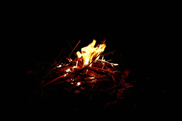 Un grande fuoco ardente fatto di bastoni sullo sfondo del cielo notturno e della spiaggia sabbiosa — Foto Stock