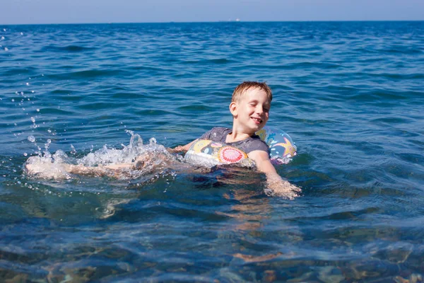 Plavovlasý chlapec leží v nafukovacím kruhu a koupe se v moři — Stock fotografie