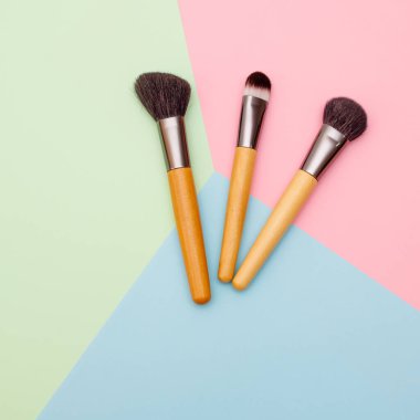 Makyaj ve yüz düzeltme için profesyonel fırçalar metin için metin alanı olan renkli bir arkaplanda yatar