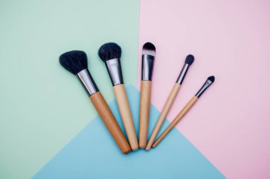 Makyaj ve yüz düzeltme için profesyonel fırçalar metin için metin alanı olan renkli bir arkaplanda yatar