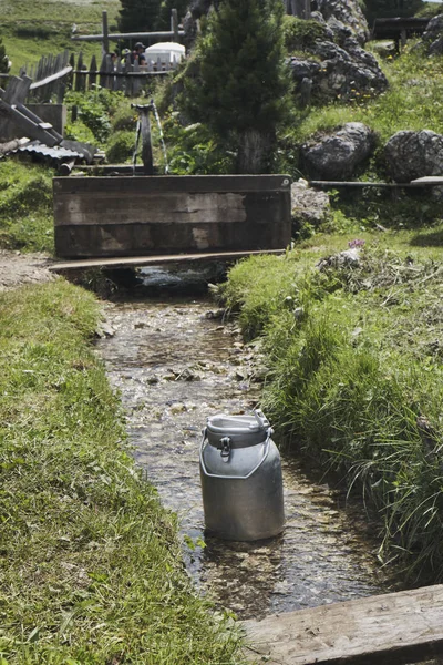 Mountain landscape with milk container on the brook