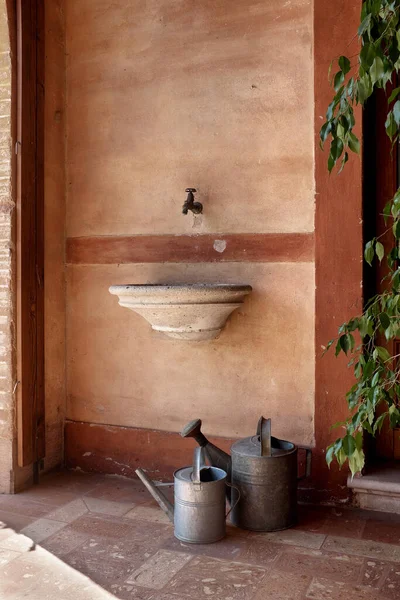 Wall with stone sink and watering cans