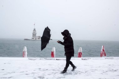 Bakire Kulesi (Kiz Kulesi) karlı kış ve İstanbul, Türkiye 'den insanlar şemsiyeyle yürüyor