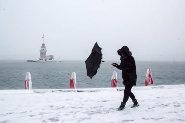Bakire Kulesi (Kiz Kulesi) karlı kış ve İstanbul, Türkiye 'den insanlar şemsiyeyle yürüyor