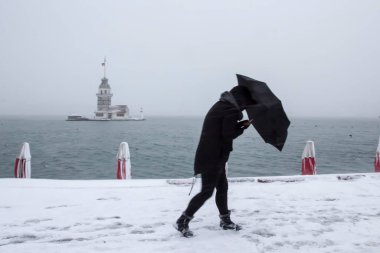 Bakire Kulesi (Kiz Kulesi) karlı kış ve İstanbul, Türkiye 'den insanlar şemsiyeyle yürüyor