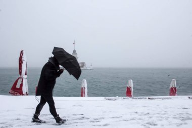 Bakire Kulesi (Kiz Kulesi) karlı kış ve İstanbul, Türkiye 'den insanlar şemsiyeyle yürüyor