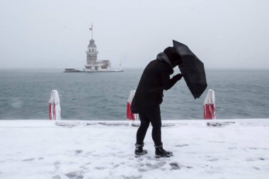 Bakire Kulesi (Kiz Kulesi) karlı kış ve İstanbul, Türkiye 'den insanlar şemsiyeyle yürüyor