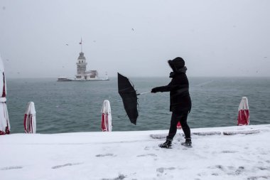 Bakire Kulesi (Kiz Kulesi) karlı kış ve İstanbul, Türkiye 'den insanlar şemsiyeyle yürüyor