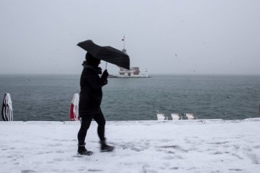Bakire Kulesi (Kiz Kulesi) karlı kış ve İstanbul, Türkiye 'den insanlar şemsiyeyle yürüyor