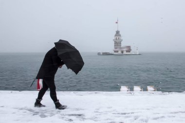 Bakire Kulesi (Kiz Kulesi) karlı kış ve İstanbul, Türkiye 'den insanlar şemsiyeyle yürüyor