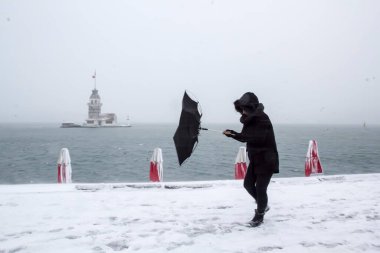 Bakire Kulesi (Kiz Kulesi) karlı kış ve İstanbul, Türkiye 'den insanlar şemsiyeyle yürüyor
