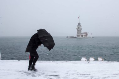 Bakire Kulesi (Kiz Kulesi) karlı kış ve İstanbul, Türkiye 'den insanlar şemsiyeyle yürüyor