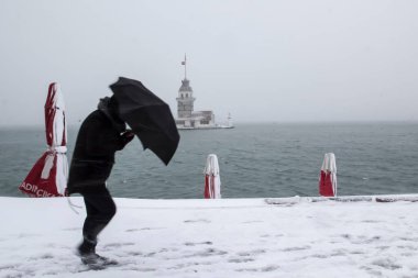 Bakire Kulesi (Kiz Kulesi) karlı kış ve İstanbul, Türkiye 'den insanlar şemsiyeyle yürüyor