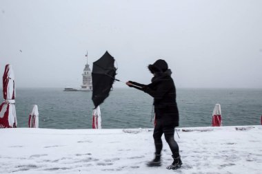Bakire Kulesi (Kiz Kulesi) karlı kış ve İstanbul, Türkiye 'den insanlar şemsiyeyle yürüyor