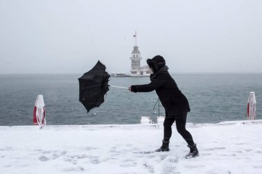 Bakire Kulesi (Kiz Kulesi) karlı kış ve İstanbul, Türkiye 'den insanlar şemsiyeyle yürüyor