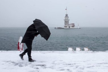 Bakire Kulesi (Kiz Kulesi) karlı kış ve İstanbul, Türkiye 'den insanlar şemsiyeyle yürüyor