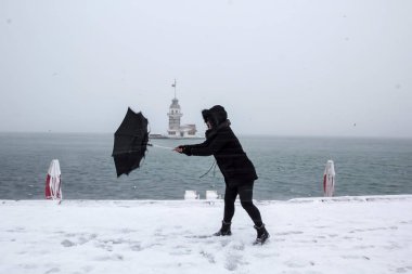 Bakire Kulesi (Kiz Kulesi) karlı kış ve İstanbul, Türkiye 'den insanlar şemsiyeyle yürüyor