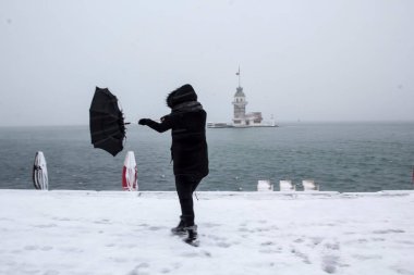 Bakire Kulesi (Kiz Kulesi) karlı kış ve İstanbul, Türkiye 'den insanlar şemsiyeyle yürüyor