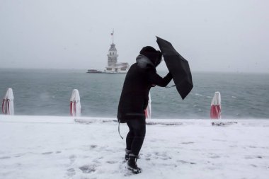 Bakire Kulesi (Kiz Kulesi) karlı kış ve İstanbul, Türkiye 'den insanlar şemsiyeyle yürüyor