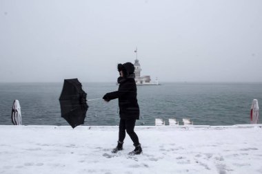 Bakire Kulesi (Kiz Kulesi) karlı kış ve İstanbul, Türkiye 'den insanlar şemsiyeyle yürüyor