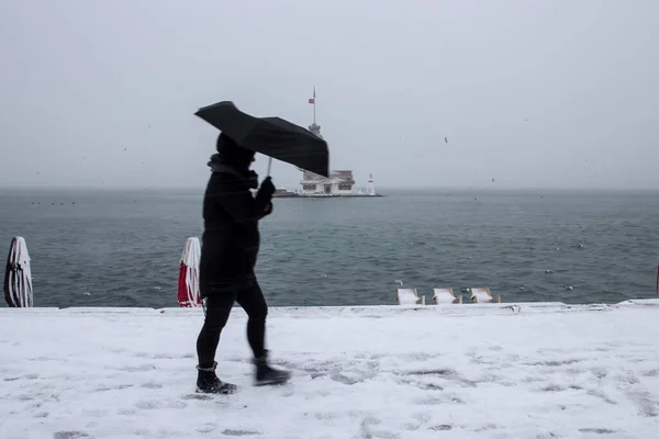 乙女の塔 Kiz Kulesi 雪と冬と人々はイスタンブール トルコから傘で歩いています ストックフォト