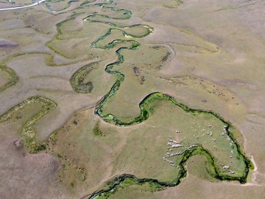 Türkiye 'nin Ordu kentindeki Persembe Platosu' nda yılan kanatlılara ait hava manzarası. Dolambaçlı bir nehir, tepelerdeki geleneksel evleri olan yeşil bir vadiden akar. Karadeniz dağlarının eşsiz coğrafi örüntüsü parlak bir yaz gökyüzü altında.