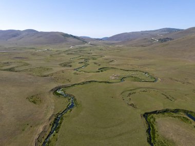 Ordu, Türkiye 'deki Persembe Platosu' ndaki kıvrımlı nehir yataklarının geniş hava manzarası. Temiz mavi gökyüzü altında kıvrılan yılanımsı su kıvrımlı yeşil bir vadinin manzarası. Karadeniz bölgesinin yüksek rakımlı doğal güzelliği ve coğrafi harikası.