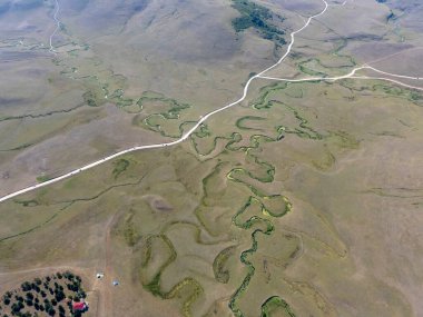 Türkiye 'nin Ordu kentindeki Persembe Platosu' nda havadan seyyar yılan manzarası. Dolambaçlı bir nehir uçsuz bucaksız yeşil ve altın bir vadiden akar. Açık bir yaz gökyüzü altında Karadeniz dağlarının çarpıcı coğrafi harikası. Doğa arkaplanı.