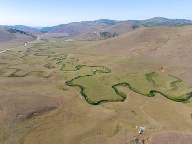 Türkiye 'nin Ordu kentindeki Persembe Platosu' nda havadan seyyar yılan manzarası. Dolambaçlı bir nehir uçsuz bucaksız yeşil ve altın bir vadiden akar. Açık bir yaz gökyüzü altında Karadeniz dağlarının çarpıcı coğrafi harikası. Doğa arkaplanı.