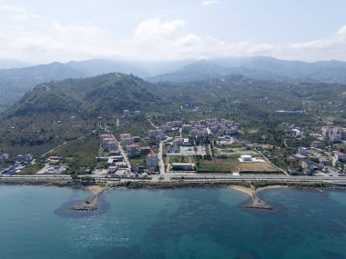 Trabzon, Türkiye 'nin Arsin ve Yomra ilçelerinin hava görüntüsü. Yeşil tepeleri, yerleşim alanları ve Karadeniz kıyıları olan kıyı kasabası doğanın ve kentsel yaşamın güzelliğini birlikte yakalıyor..