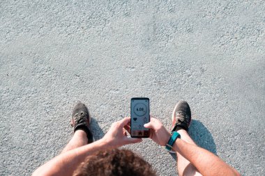 Adam dışarıda koştuktan sonra cep telefonundaki bir uygulamaya bakıyor. Cep telefonuna odaklan..