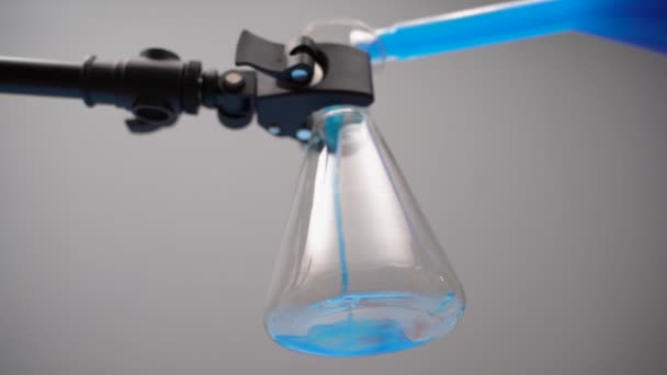 ガラスのフラスコに青い液体を注いだ。液体がエルレンマイヤー電球に流れ込む. — ストック動画