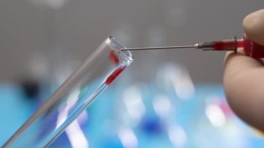 İğneden şişeye kan damlaları akıyor. Şırıngayla test tüpündeki kan.