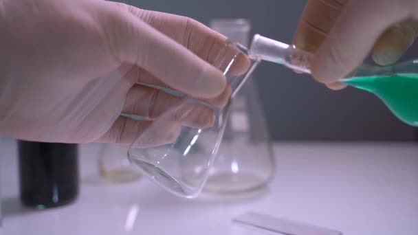 Chemicus of wetenschapper gieten vloeistof in laboratoriumkolf. Conceptonderzoek. Eerste persoon — Stockvideo
