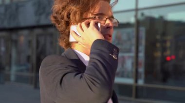 İş adamı ya da ofis çalışanı sokakta cep telefonuyla aktif olarak konuşuyor