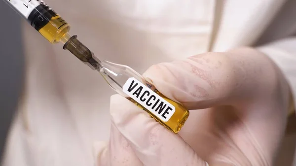 Mano de trabajador médico con guantes quirúrgicos que muestran una sonda con vacuna del Coronavirus. El médico marca la inyección de la vacuna en la jeringa — Foto de Stock
