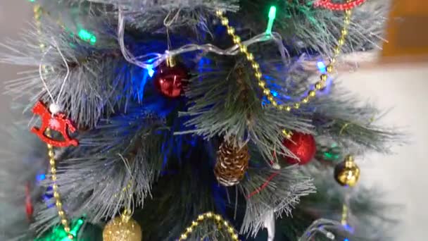 Christbaumschmuck im Zimmer. In der Nähe glitzert ein Weihnachtsbaum. Toller Lichterkranz, der Weihnachtsstimmung ausstrahlt — Stockvideo