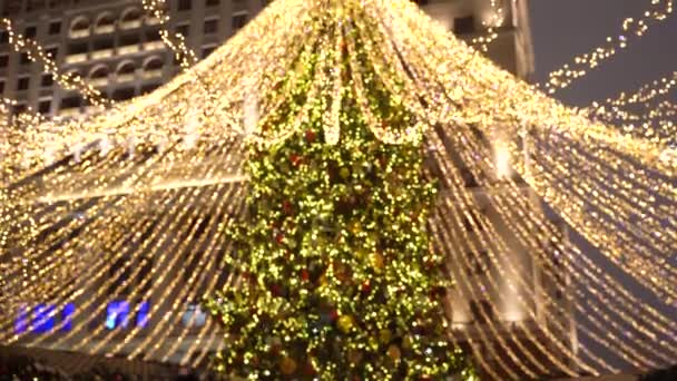 Zimní nálada ve městě, osvícení na Vánoce. Slavnostní pouliční osvětlení, rozmazaná světla vánočního stromku — Stock video