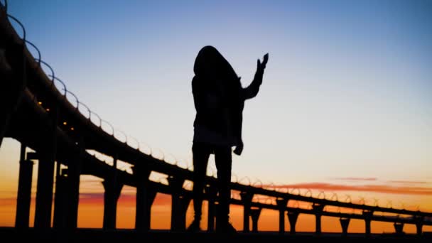 Silueta de hombre bailando al atardecer. Baile loco en el puente al lago . — Vídeos de Stock