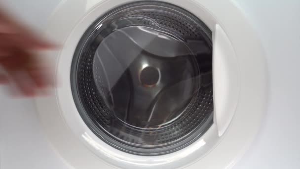 Hand putting clothes into washing machine. Hand putting clothes into the cylinder washing machine — Stock Video