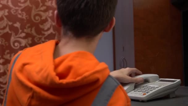 Un hombre con uniforme de trabajo naranja responde a una llamada. Equipo de Servicio al Cliente responde por teléfono — Vídeos de Stock