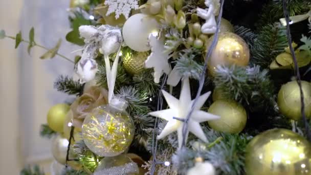 Closeup of several golden christmas balls hanging on christmas fir artificial tree. Decorated Christmas tree closeup. New Year baubles — Stock Video