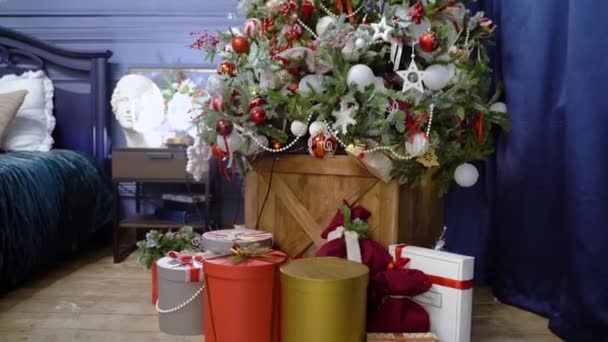 Julklappar på julafton. Gåva i en röd låda med en båge under Holidays träd. Gåva för det nya året under julgran — Stockvideo